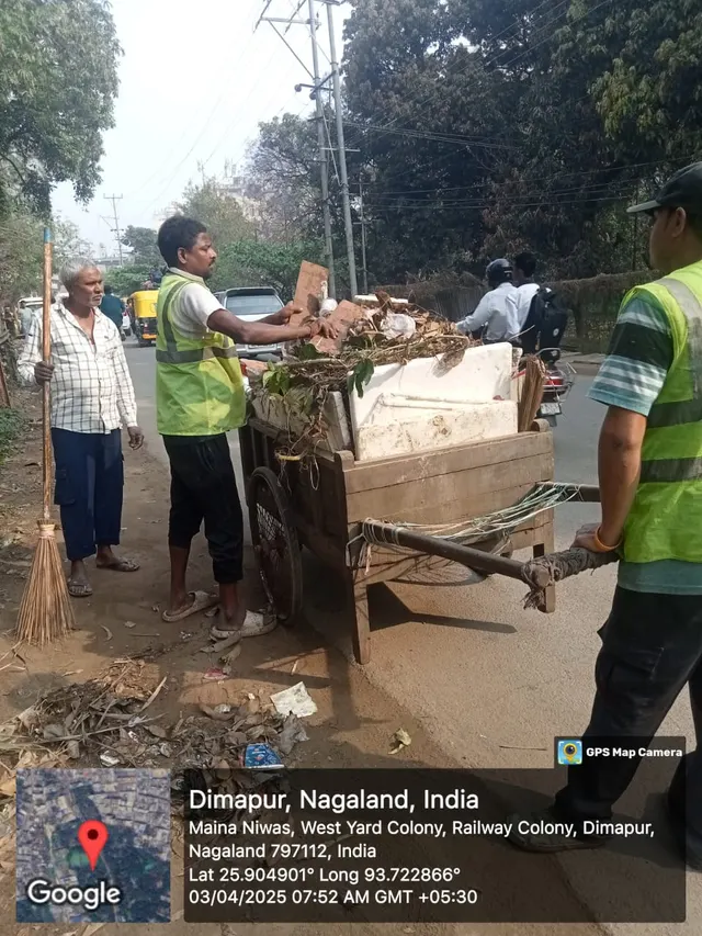 Sanitation workers loading waste from a roadside drain onto a cart