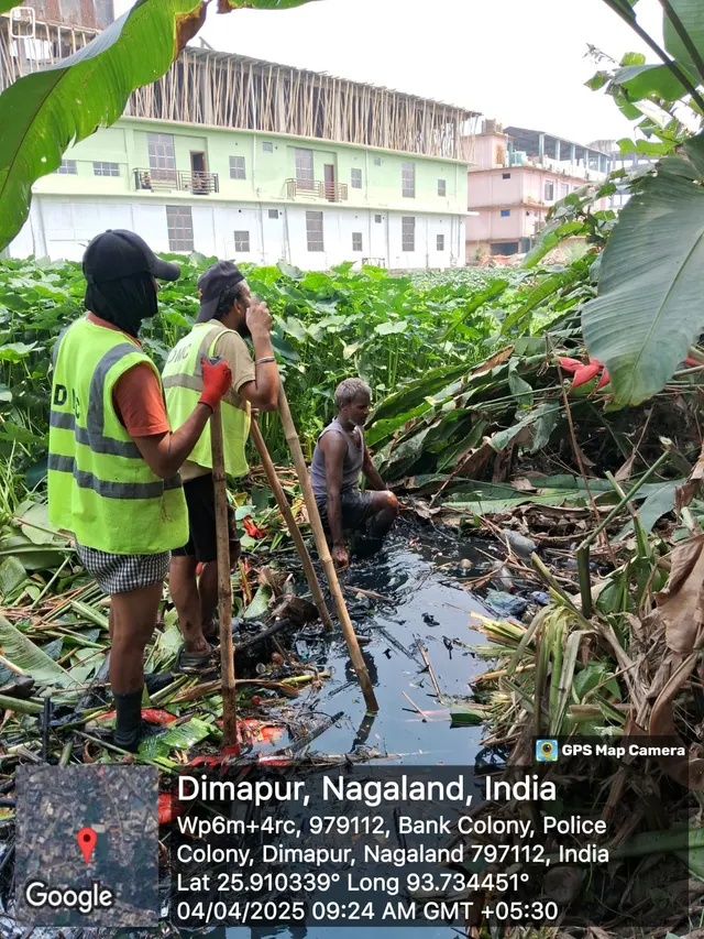 Workers clearing a clogged drain with poles