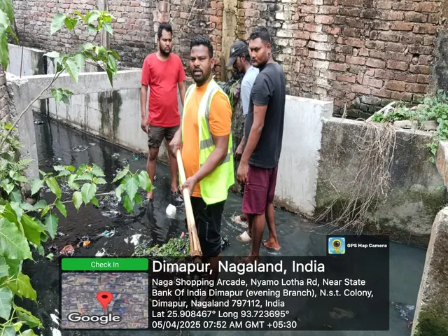 Workers and residents at a drain being cleaned behind shops